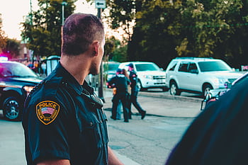Police officer monitoring a street scene with patrol vehicles in Wheeling, WV. HD wallpaper