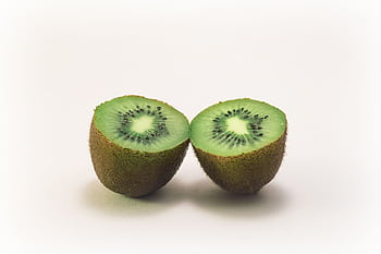 Close-up of two fresh kiwi halves displaying vibrant green color and texture, highlighting freshness and nutrition. HD wallpaper