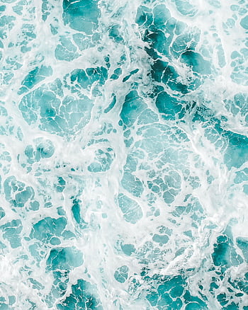 Aerial view of vibrant ocean waves and frothy seafoam creating abstract patterns. HD phone wallpaper