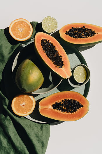 Top view of fresh papaya, lime, and orange slices on a green fabric background. HD phone wallpaper