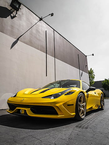 Striking yellow Ferrari sports car parked in an urban area under a clear sky. HD phone wallpaper