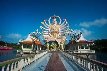 Stunning view of the Guanyin statue at Wat Plai Laem temple in Thailand, capturing its intricate design under a clear sky. HD wallpaper