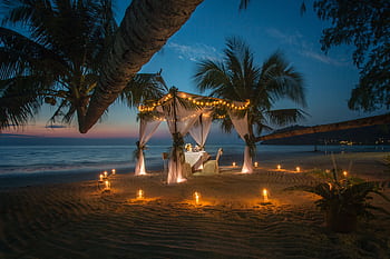 A que romantic dinner setup under a canopy on a Thai beach at twilight, surrounded by candles. HD wallpaper