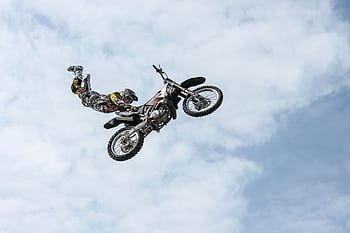 Exciting motocross action shot of a stunning aerial stunt against a bright sky. HD wallpaper