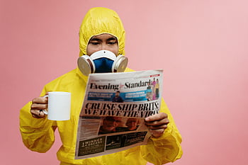 Person in yellow protective suit reading a newspaper with a mug. HD wallpaper
