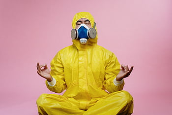 Man in protective suit and respirator practicing meditation against pink backdrop. HD wallpaper