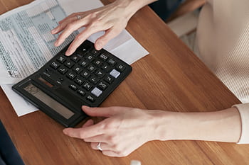 Close-up of a woman using a calculator and reviewing bills at home. HD wallpaper