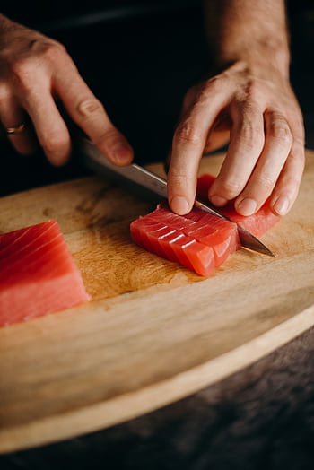 Close-up of hands slicing fresh tuna on a wooden cutting board, perfect for Asian cuisine themes. HD phone wallpaper
