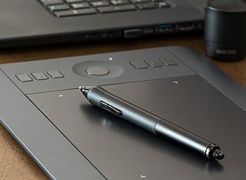 Close-up of a digital drawing tablet with a stylus pen, ideal for creative design work. HD wallpaper