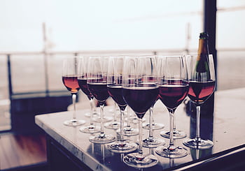 A collection of red wine glasses elegantly arranged on a bar table, perfect for events. HD wallpaper