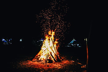 A blazing campfire outdoors at night sparks warmth and light. HD wallpaper