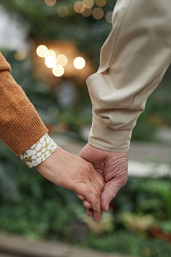 Intimate close-up of a senior couple holding hands, symbolizing love and togetherness. HD phone wallpaper