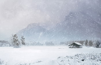 Serene winter landscape featuring a snow-covered cabin amidst mountains and trees. HD wallpaper