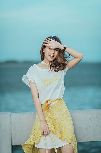 Fashionable young woman in a relaxed pose by the ocean during a sunny day. HD phone wallpaper