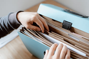 Close-up of hands organizing papers in a blue folder, ideal for business and office concepts. HD wallpaper
