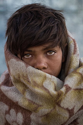 Boy with expressive eyes wrapped in blanket outdoors, showcasing innocence and warmth. HD phone wallpaper