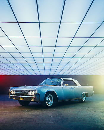 A vintage classic car displayed indoors with modern lighting, showcasing style and elegance. HD phone wallpaper