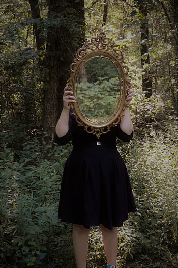 A woman holds an ornate mirror in a forest setting, reflecting nature. HD phone wallpaper