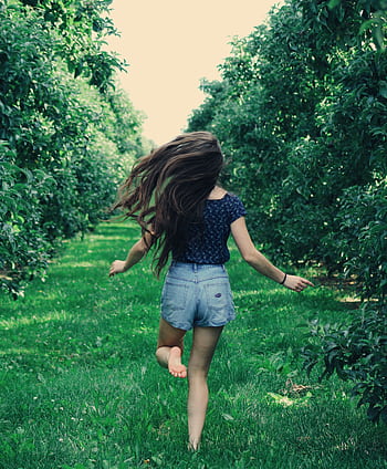 A girl joyfully runs through a sunlit orchard, enjoying nature and dom. HD phone wallpaper