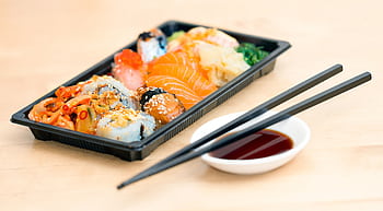 A mouthwatering assortment of sushi rolls and sashimi served with soy sauce and chopsticks. HD wallpaper