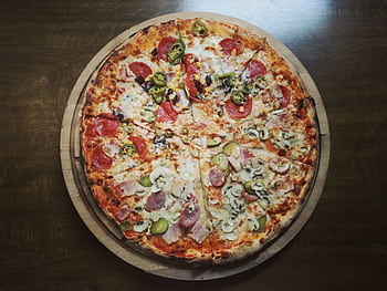 Close-up of a delicious pepperoni and salami pizza on a wooden table, featuring mushrooms and jalapenos. HD wallpaper