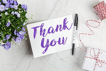 A stylish thank you card paired with purple flowers, a gift box, and pen on a marble surface. HD wallpaper
