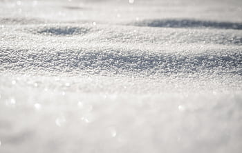 A detailed view of a pristine snowy surface, capturing the soft texture and light reflections, perfect for winter themes. HD wallpaper