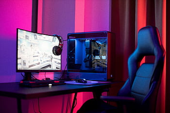 A sleek gaming setup featuring a high-end PC, monitor, and ergonomic chair lit by neon lights. HD wallpaper