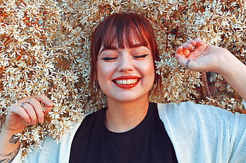 Redhead woman smiling with closed eyes, surrounded by blooming flowers, radiating joy and happiness. HD wallpaper