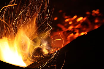 Long exposure shot of dynamic flames and sparks creating a warm atmosphere at night. HD wallpaper
