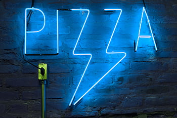 Vibrant blue neon sign spelling 'pizza' against a textured brick wall backdrop. HD wallpaper
