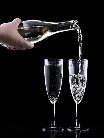 Elegant champagne being poured into two flutes against a black background, highlighting celebration and luxury. HD phone wallpaper