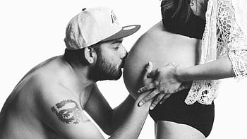A couple sharing an intimate moment during pregnancy, highlighting love and parenthood. HD wallpaper