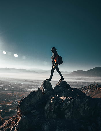 A lone hiker conquering rocky peaks in Nawur, Afghanistan under a clear sky. HD phone wallpaper