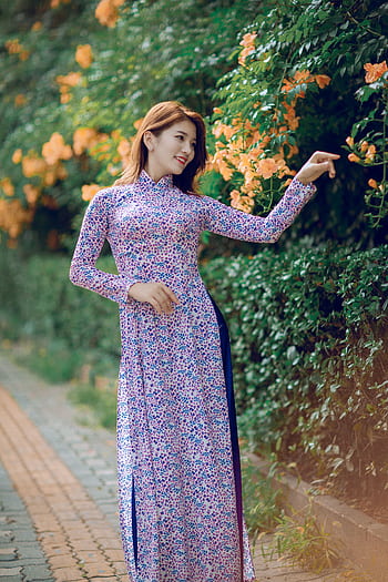 Beautiful Asian woman in a floral dress, posing by vibrant flowers outdoors. HD phone wallpaper