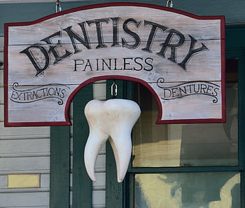 Classic dental sign with a hanging tooth, advertising painless extractions and dentures. HD wallpaper