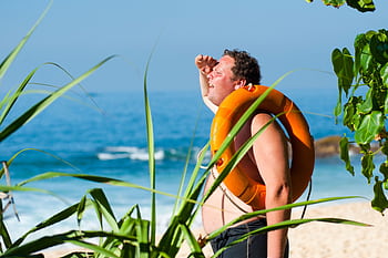A man with a lifebuoy enjoys a sunny day at the beautiful tropical beach of Unawatuna, Sri Lanka. HD wallpaper