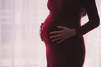 Silhouette of a pregnant woman gently holding her belly, emphasizing motherhood and anticipation. HD wallpaper
