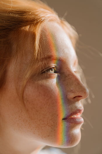 Elegant portrait of a redhead woman with rainbow light across her face, highlighting freckles and beauty. HD phone wallpaper