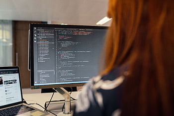 A female engineer works on code in a contemporary office setting, showcasing software development. HD wallpaper