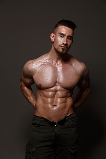 Portrait of a muscular shirtless male model posing confidently in a studio setting. HD phone wallpaper