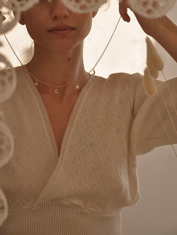 A woman gracefully adjusts a delicate necklace, creating a serene and elegant atmosphere. HD phone wallpaper