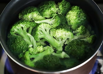 Bright green broccoli florets boiling in a pot for a fresh, healthy meal. HD wallpaper