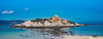 Panoramic view of a tranquil beach with stunning rock formations under a clear blue sky. HD wallpaper