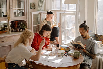A group of college students studying in a bright, cozy room with natural light. HD wallpaper