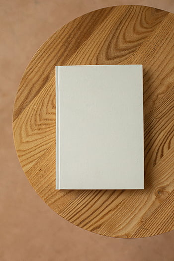 Top view of a simple, blank white book on a round wooden table, ideal for mockup designs. HD phone wallpaper