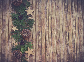 Rustic wooden background with festive pine cones, stars, and greenery for Christmas decoration. HD wallpaper