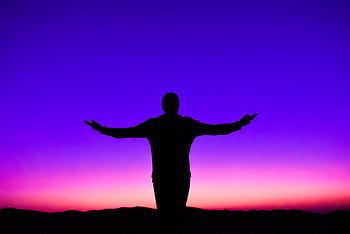 Silhouette of a person with outstretched arms against a vivid sunset sky. HD wallpaper