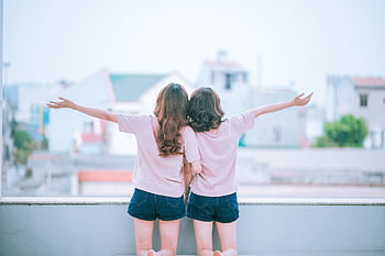 Two women embracing while facing a scenic backdrop, sharing joyful moments. HD wallpaper