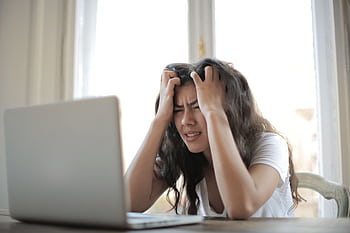Frustrated woman struggling with remote work stress and digital challenges indoors. HD wallpaper